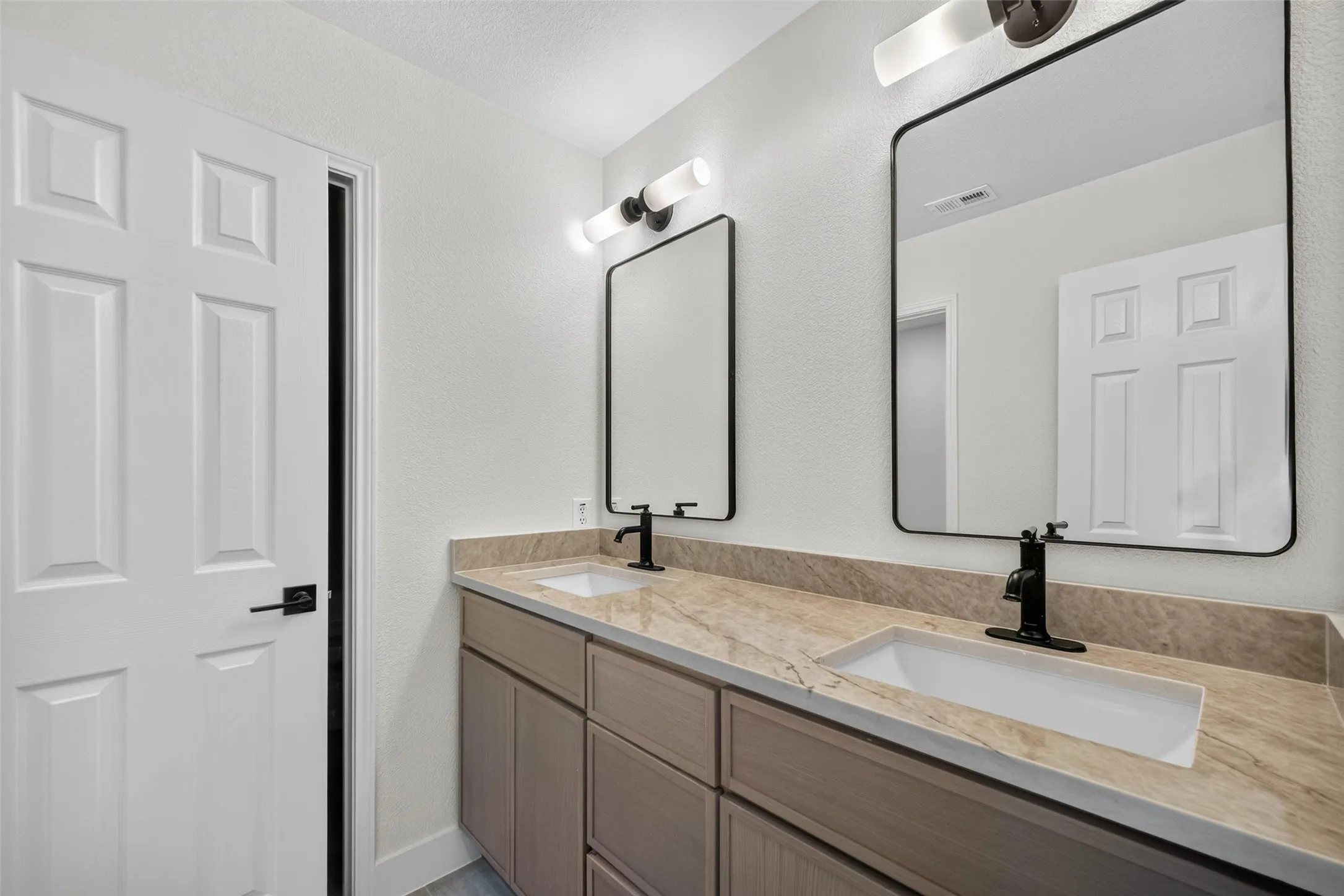 Dual rectangular vessel sinks with matte black faucets, set into a stone-finish countertop