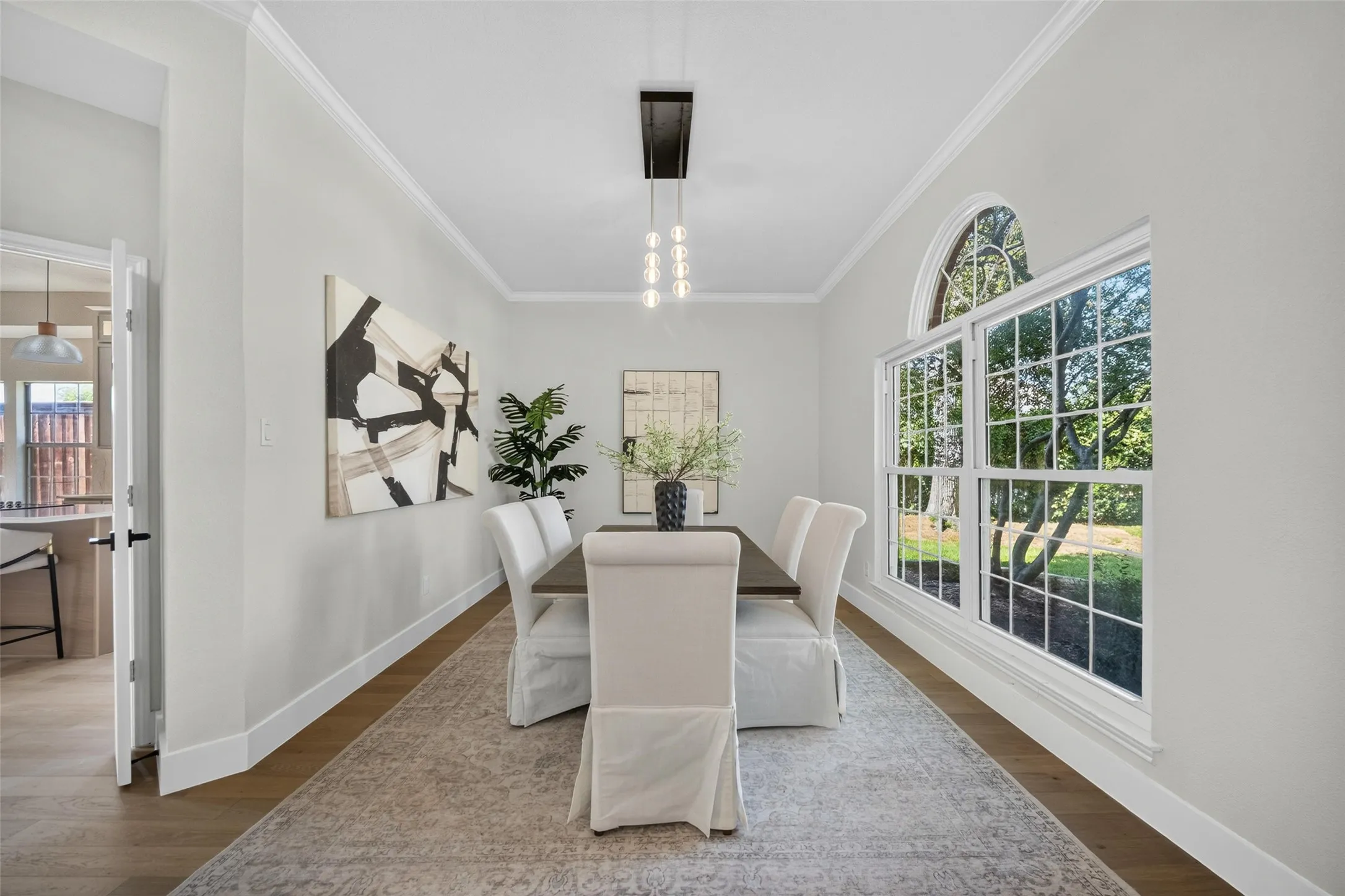 Wood-finish flooring, crown molding, and a chandelier with glass globes
