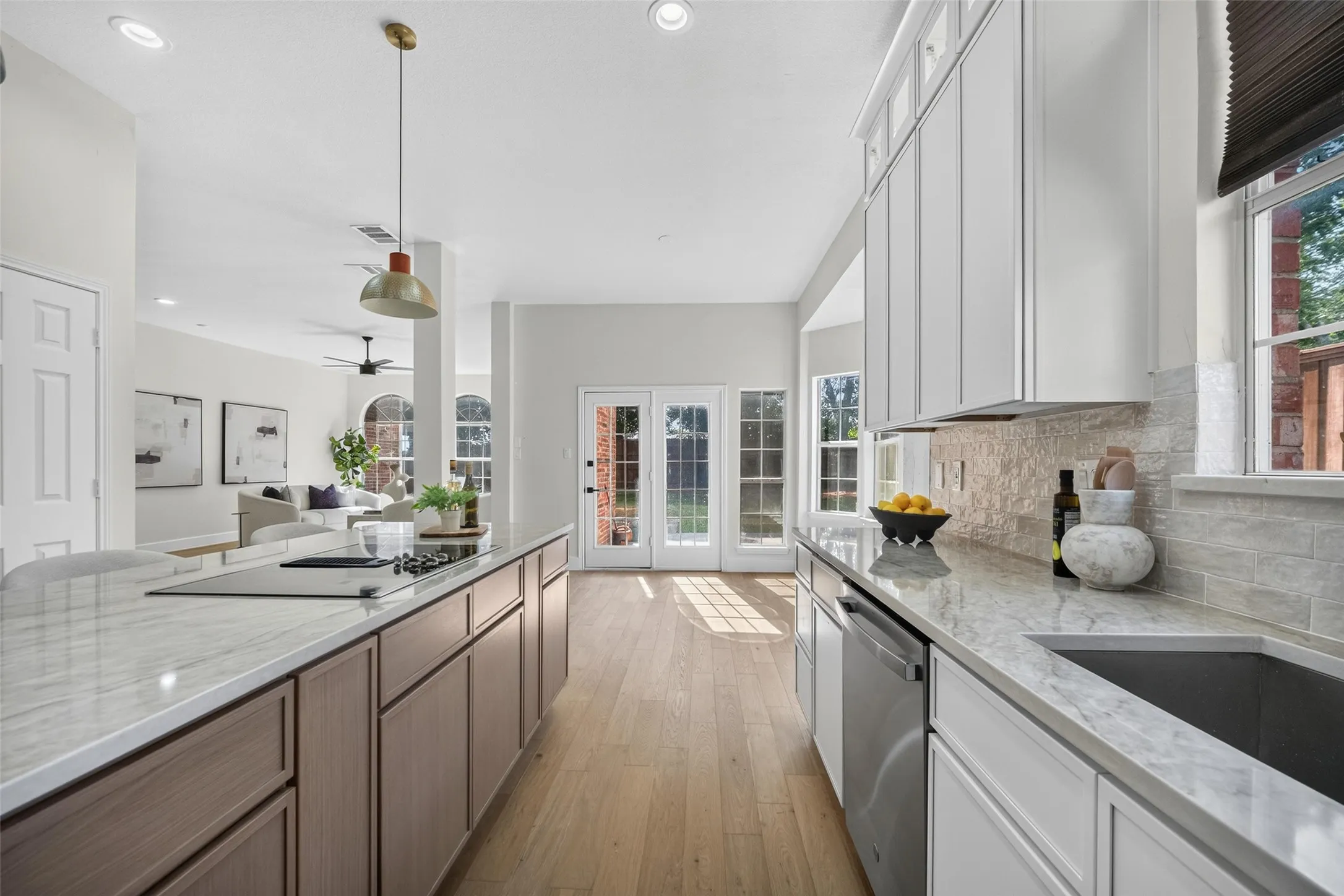 Kitchen featuring light wood-finish flooring, recessed lighting, an expansive island with a built-in cooktop, light-toned countertops, and white cabinetry