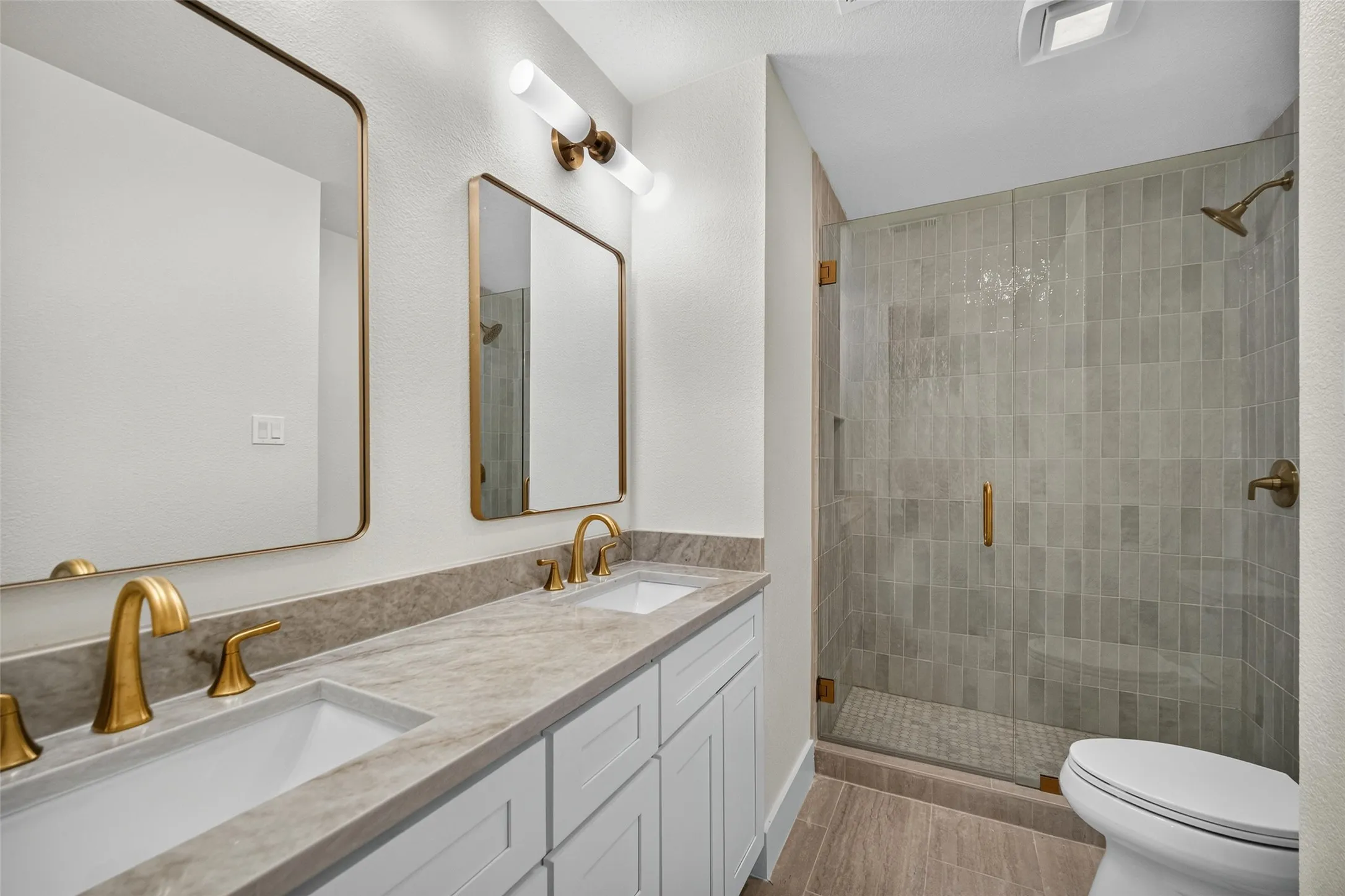 Double vanity with undermount sinks, gold-tone fixtures, and framed mirrors