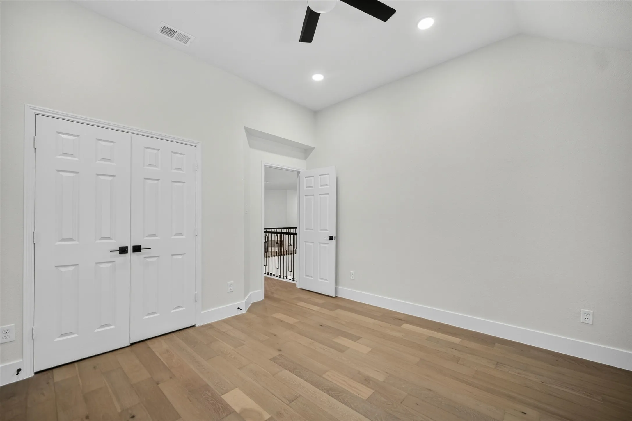 Vaulted ceiling, recessed lighting, wood-finish flooring, two-panel interior doors, and a ceiling fan