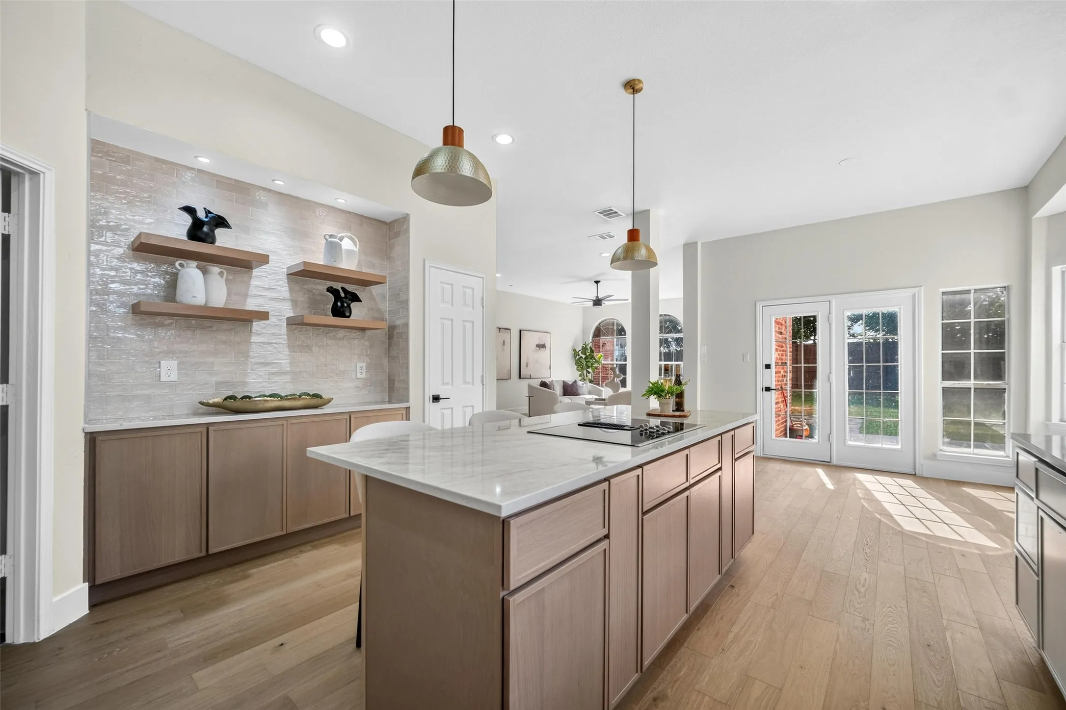 Open-concept kitchen with a central island, light wood-finish flooring, and white countertops