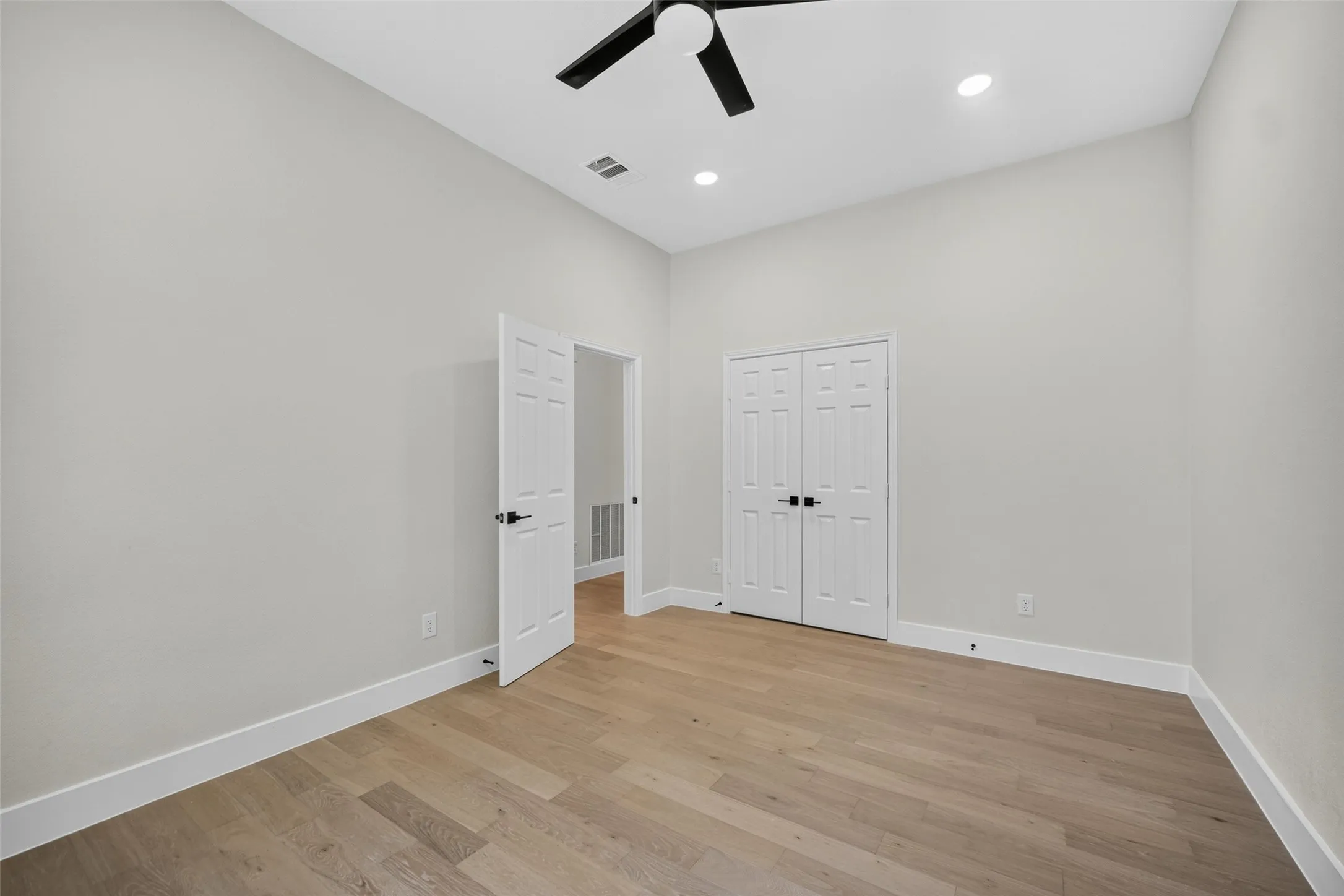 Vaulted ceiling with a ceiling fan, recessed lighting, wood-finish flooring, and white trim