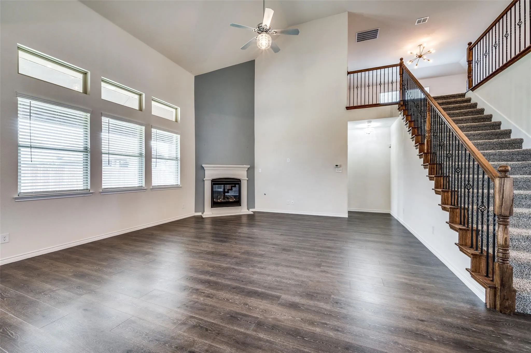 Vaulted ceilings, wood-finish flooring, staircase with wrought iron balusters, fireplace with mantel, and transom windows