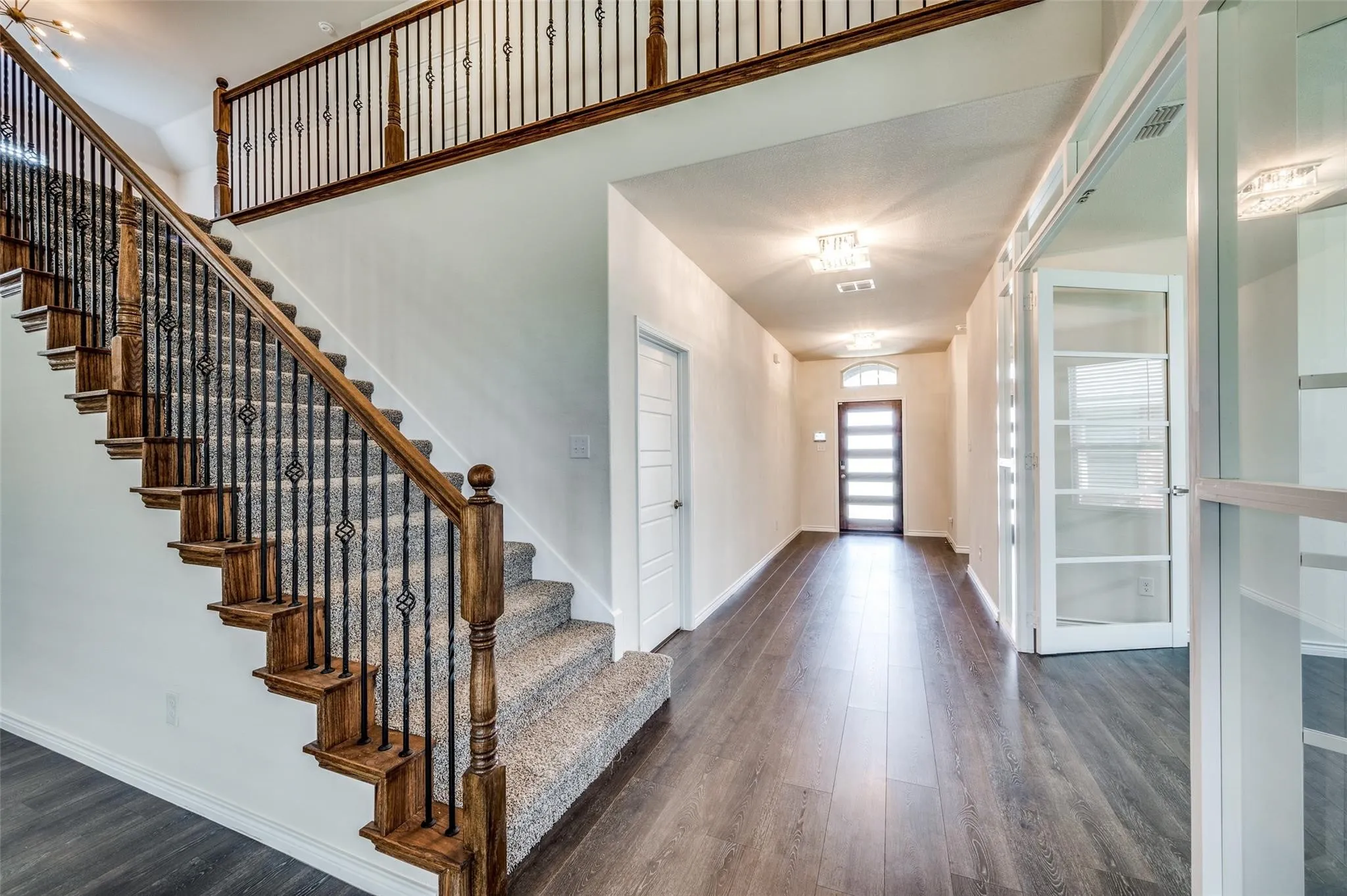 Grand staircase with wrought iron balusters and wood-finish handrail