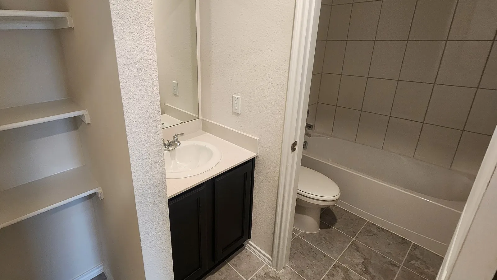 Vanity with integrated sink, dark wood-finish cabinetry, and neutral countertop