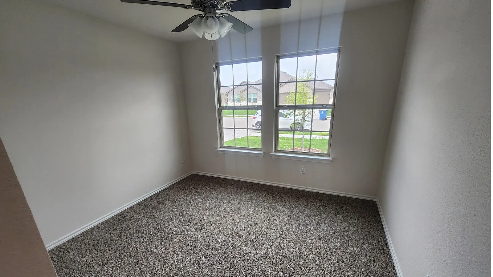 Dual pane windows with grid pattern, neutral tone walls, and textured carpet flooring