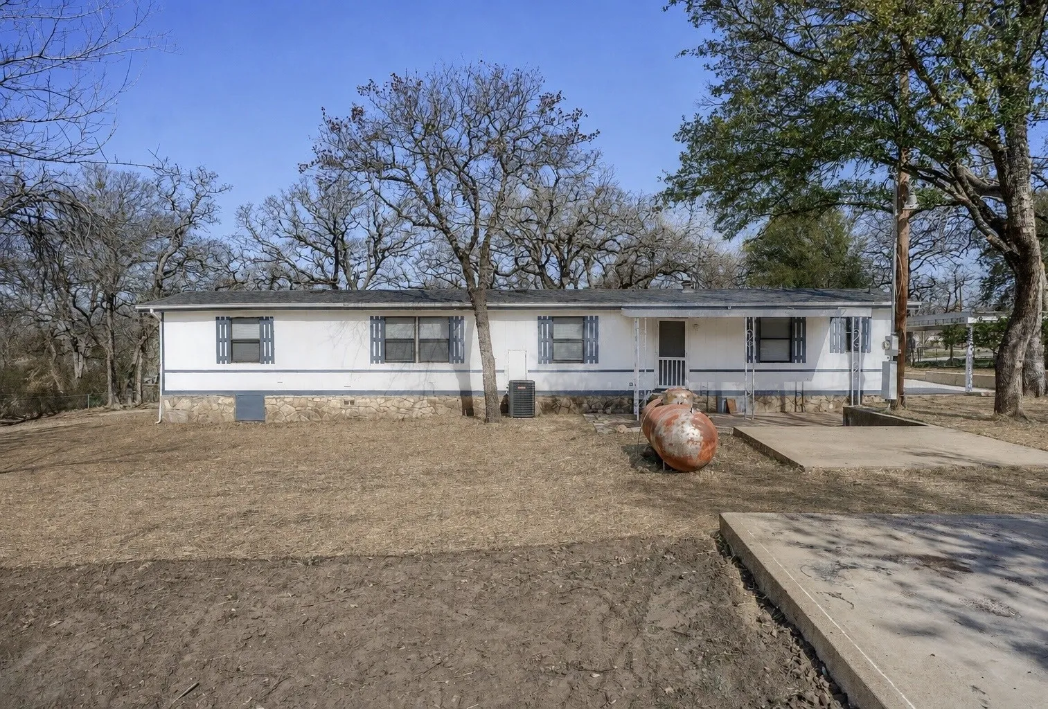 Single-story residence featuring a white exterior with blue trim, a stone-finish foundation, and multiple windows