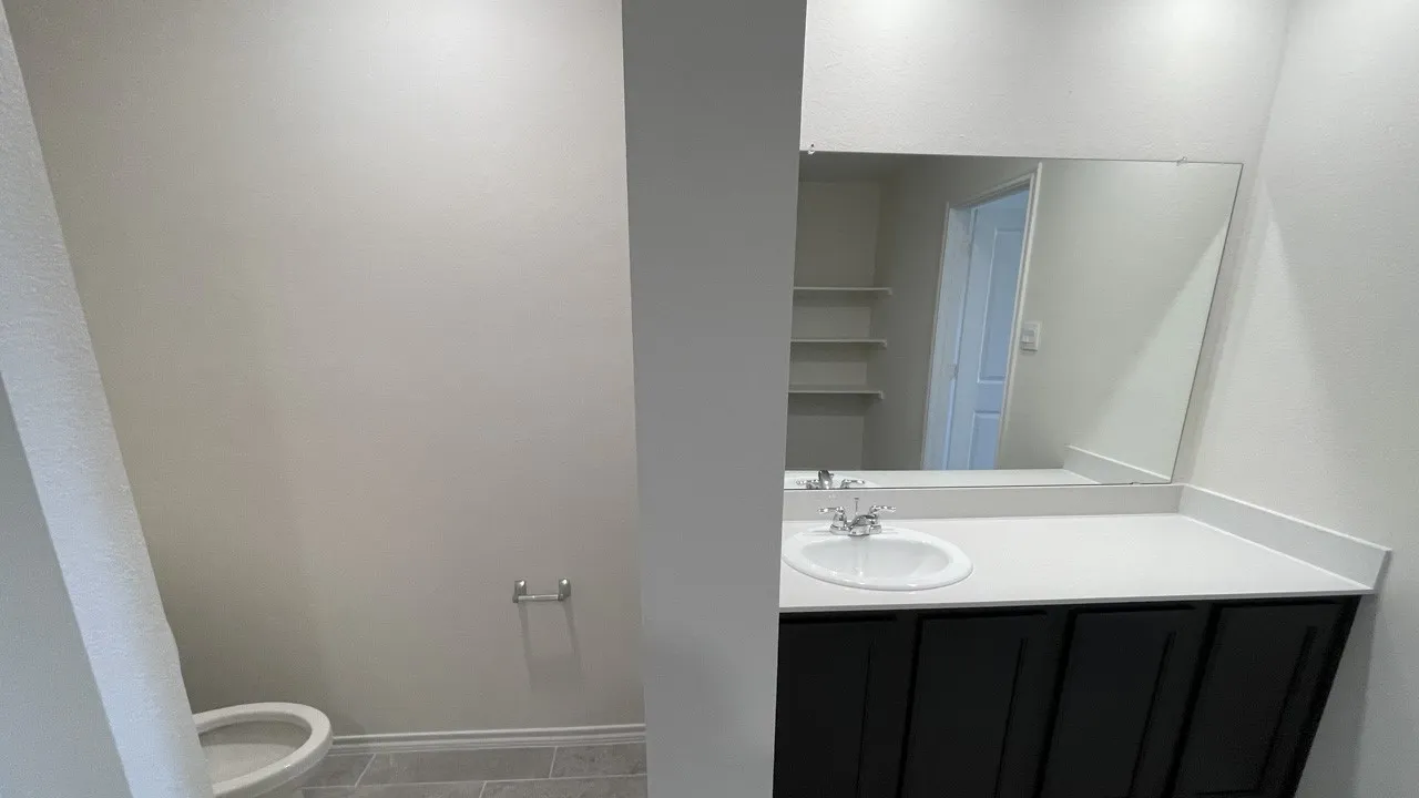 Vanity with an integrated sink, polished chrome faucet, and expansive wall-mounted mirror