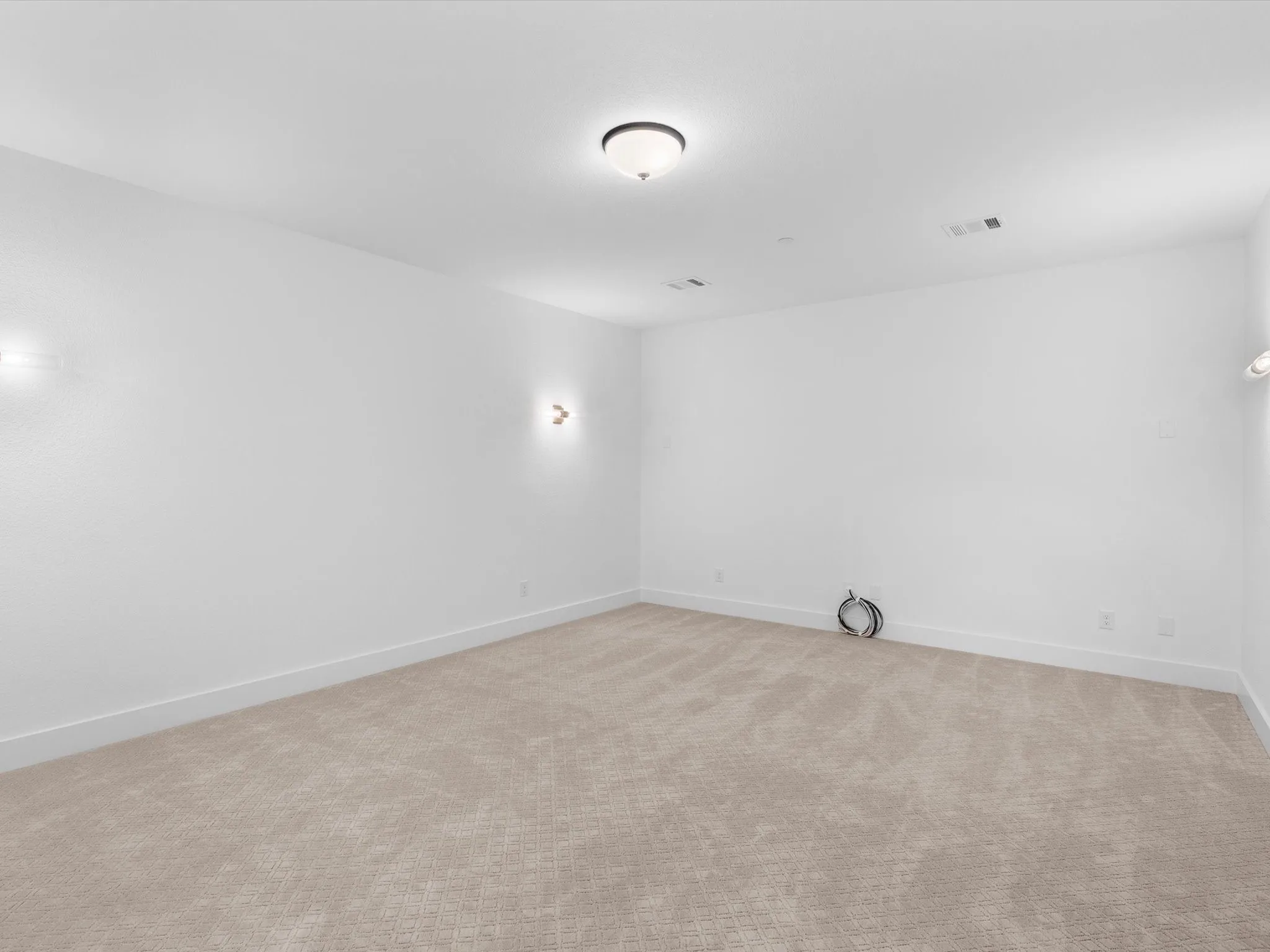 Carpeted flooring, neutral wall tones, flush-mount ceiling light, and wall sconces