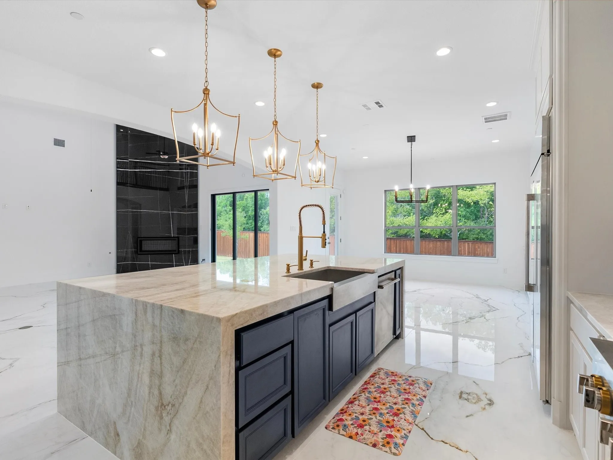 Central kitchen island with waterfall countertop, integrated farmhouse sink, and under-cabinet storage