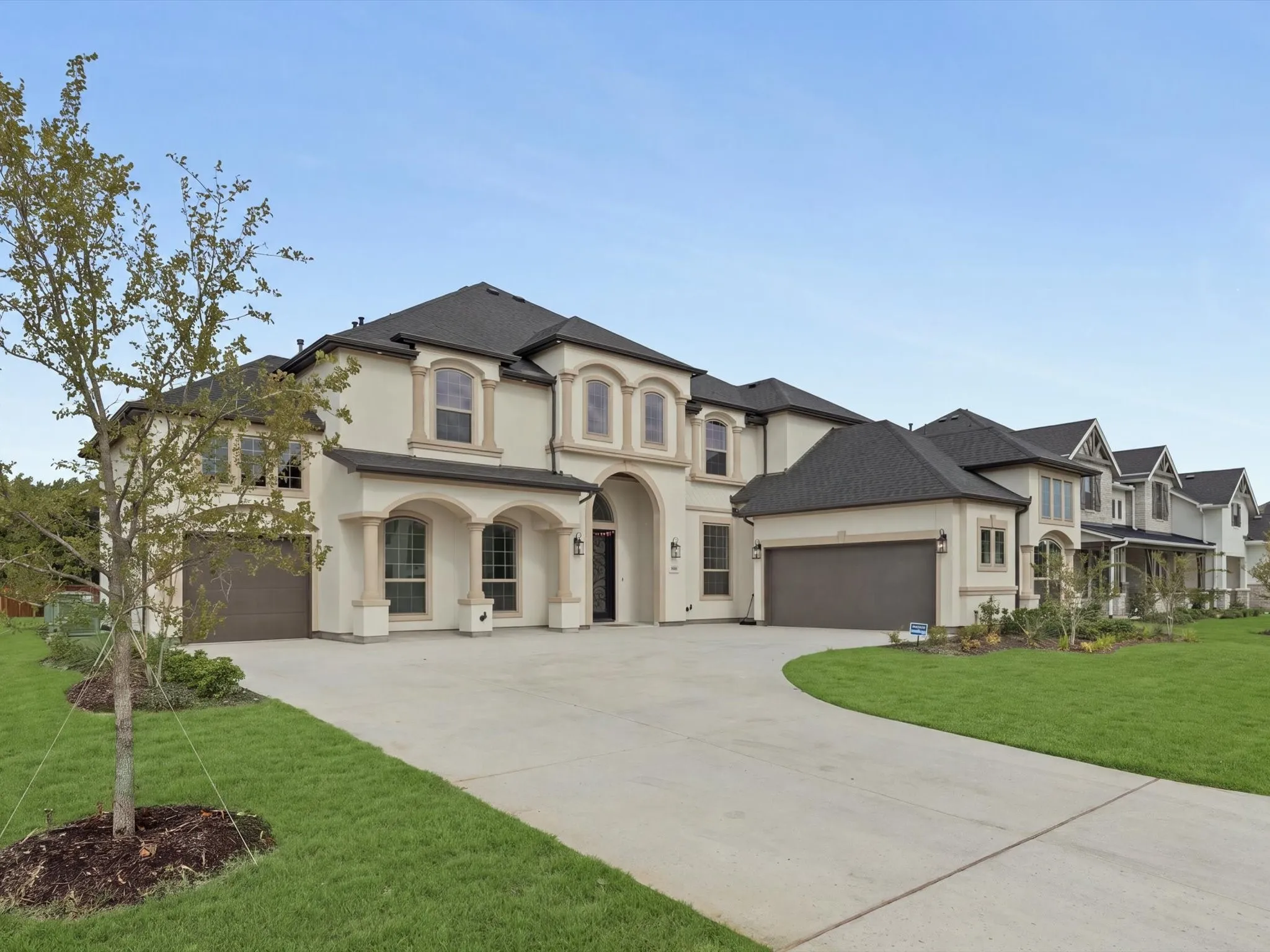 Stucco exterior with stone accents, arched windows, and a concrete driveway