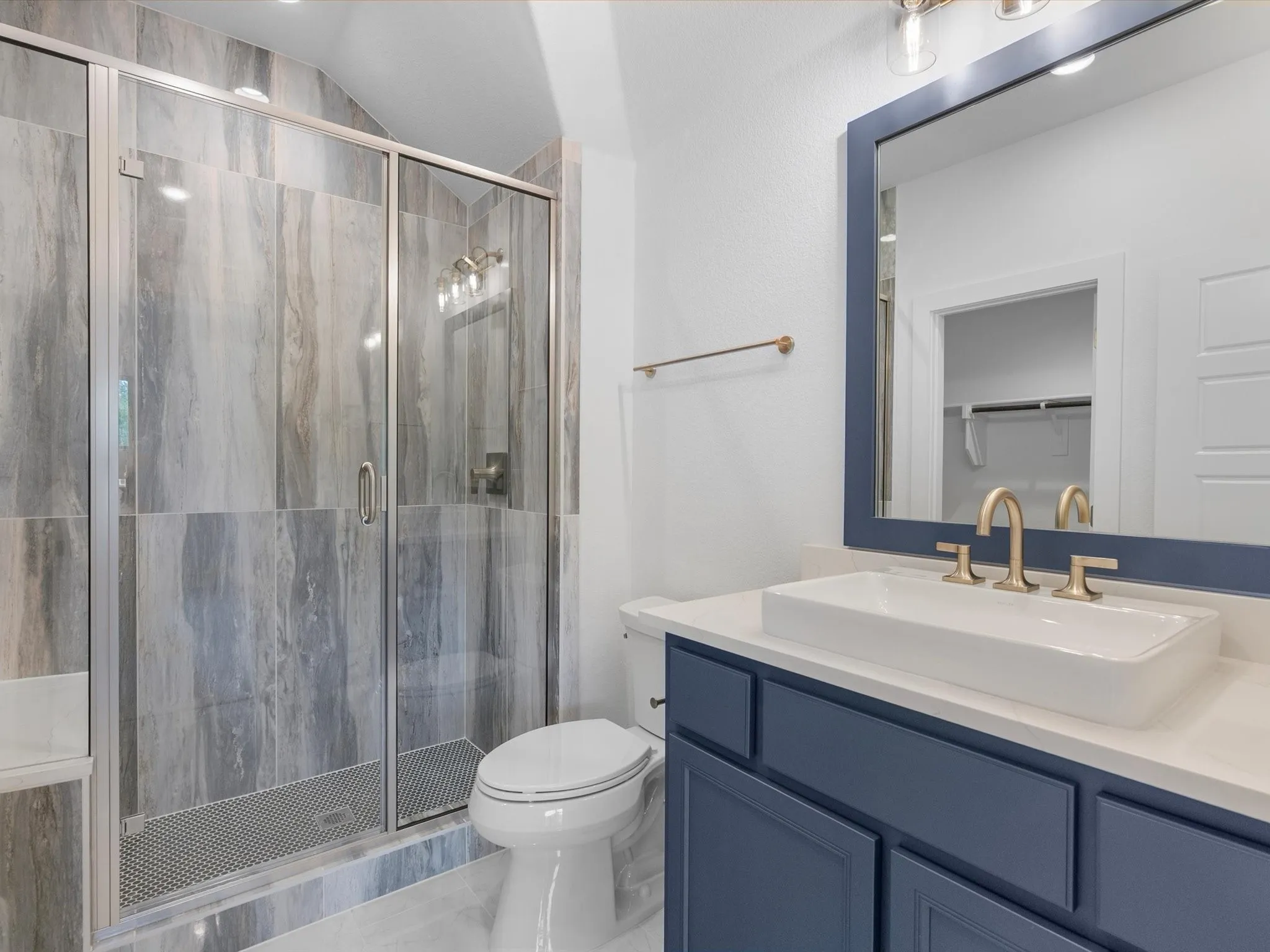 Glass-enclosed shower with full-height stone-look tile, a single-handle faucet, and overhead lighting