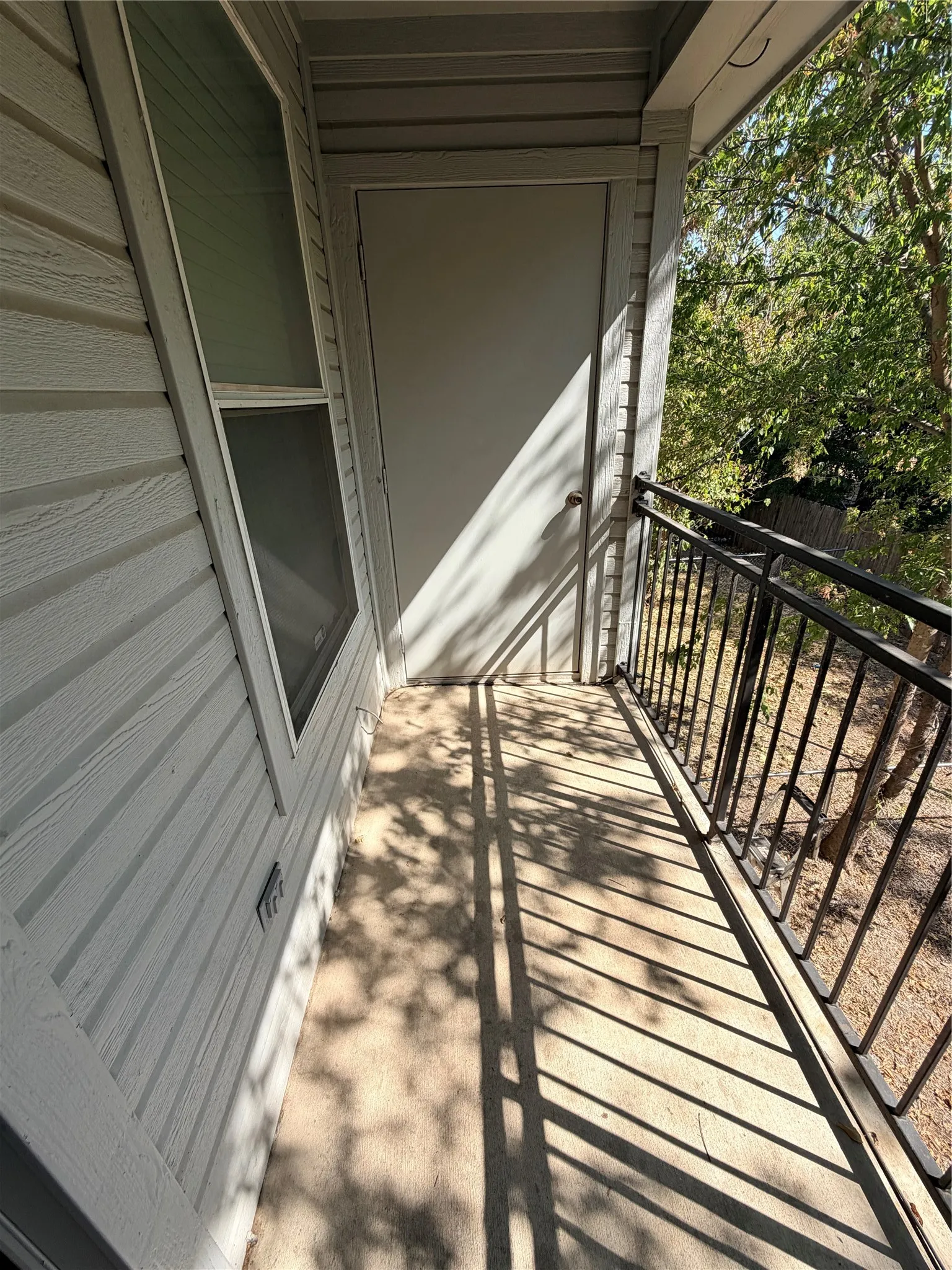Outdoor balcony with a black metal railing and concrete flooring