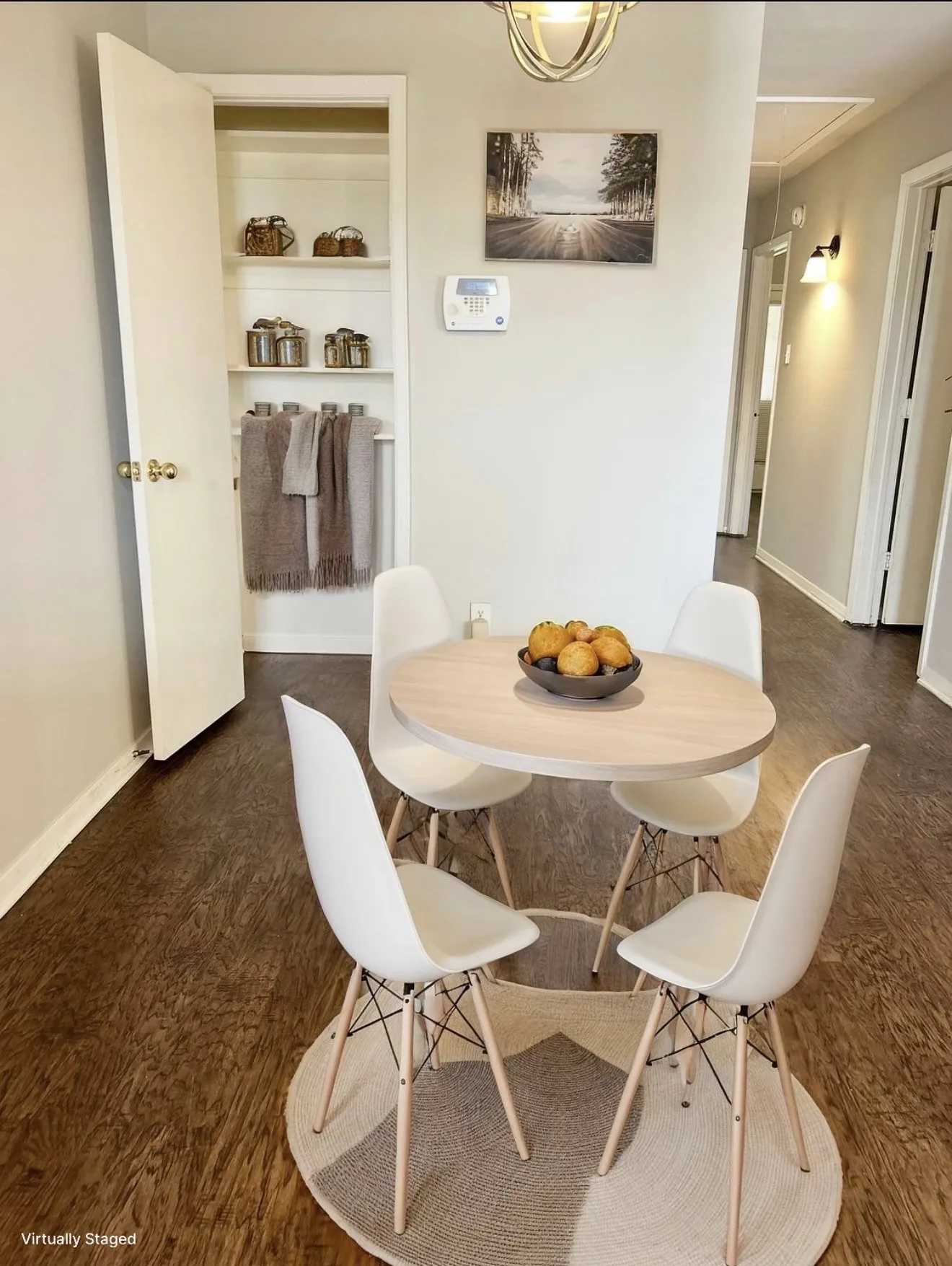 Wood-finish flooring, built-in shelving, wall-mounted thermostat, and an overhead lighting fixture