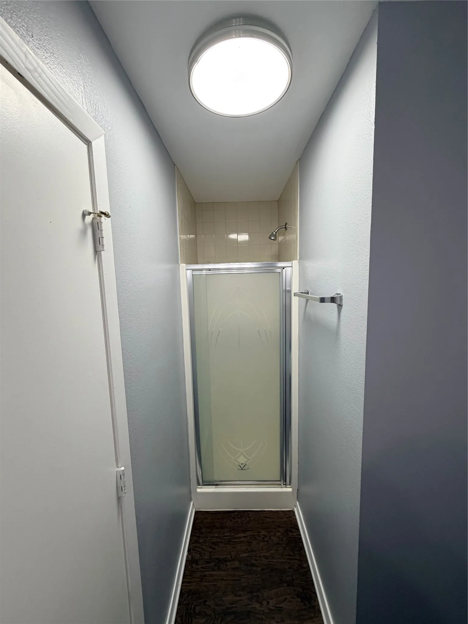 Shower stall with glass enclosure, chrome fixtures, and tiled surround