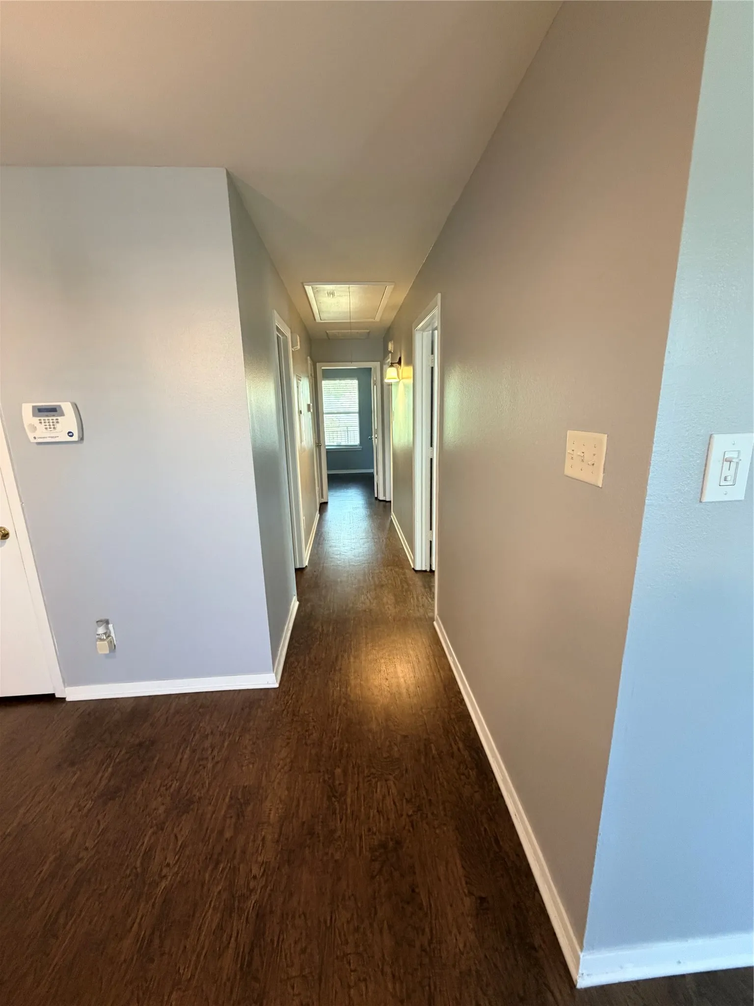 Hallway featuring wood-finish flooring, light gray walls, white trim, and a ceiling light fixture