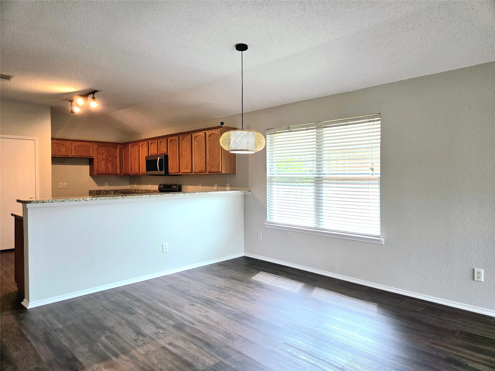 Wood-finish flooring, recessed lighting, wood cabinetry, granite-look countertops, and a built-in microwave