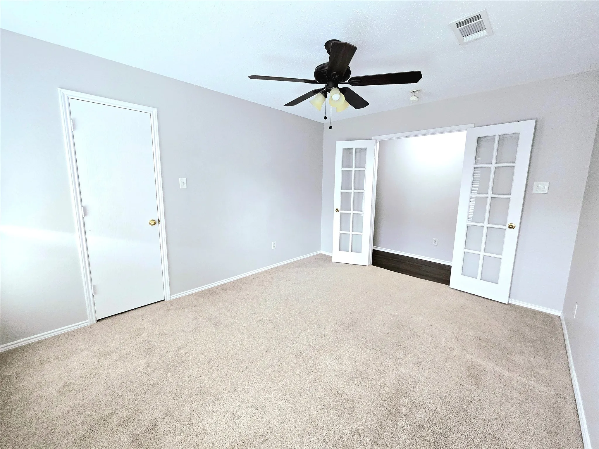 Neutral-toned carpeting, light gray wall paint, and a ceiling fan with integrated lighting