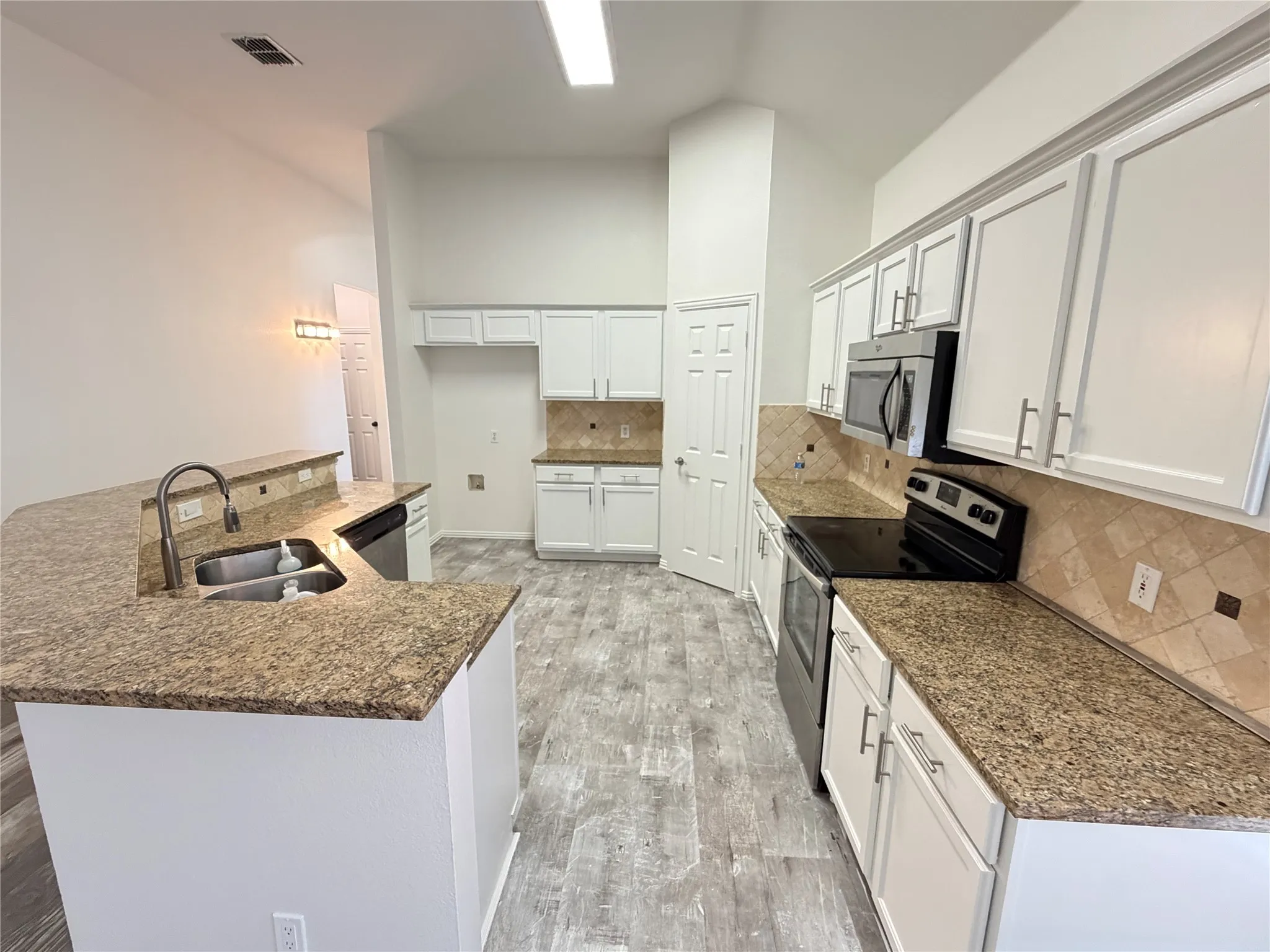 Kitchen featuring wood-finish flooring, light cabinetry, granite countertops, and a tile backsplash