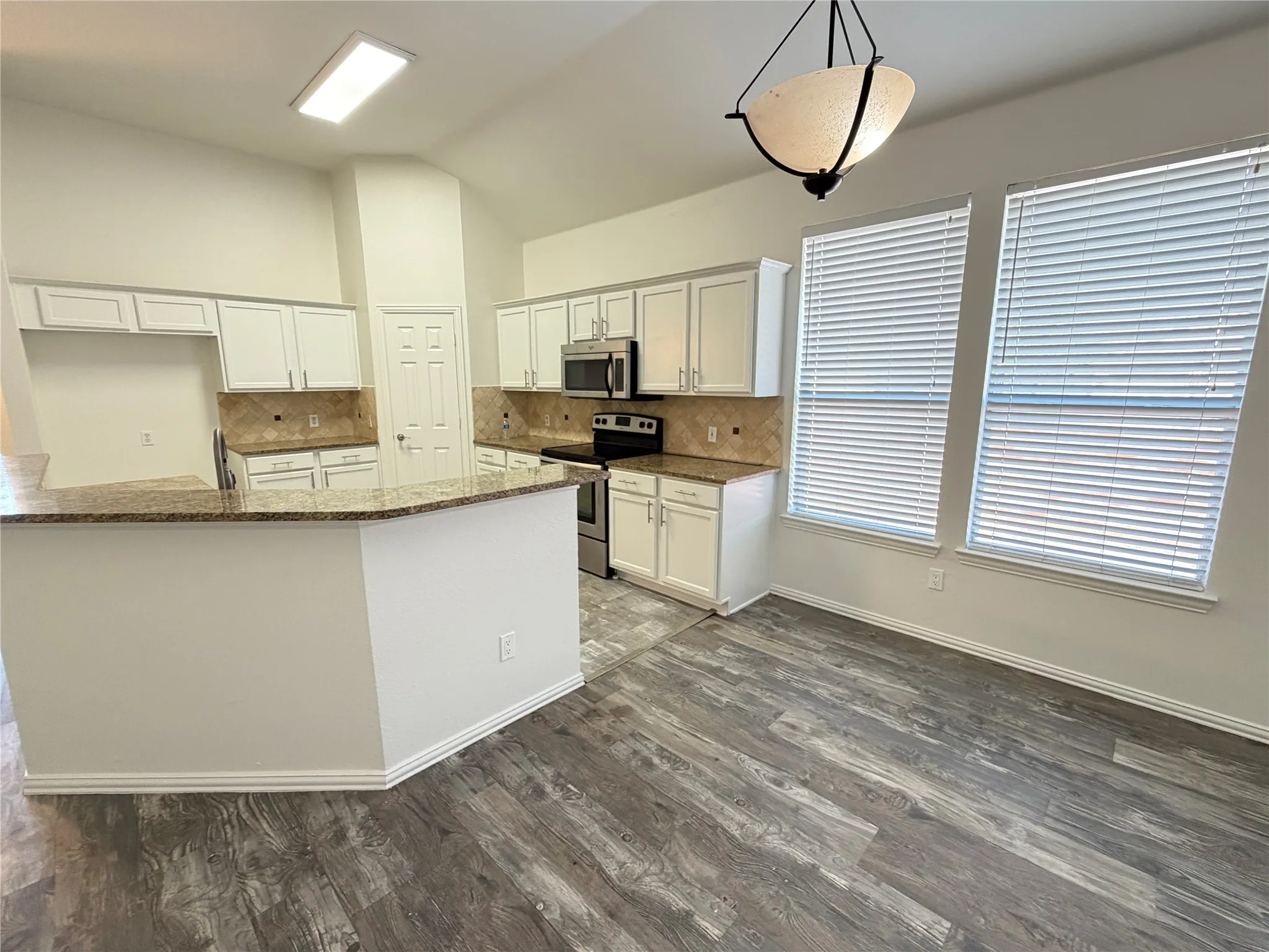 Kitchen featuring white cabinetry, granite countertops, stainless steel appliances, and a tile backsplash