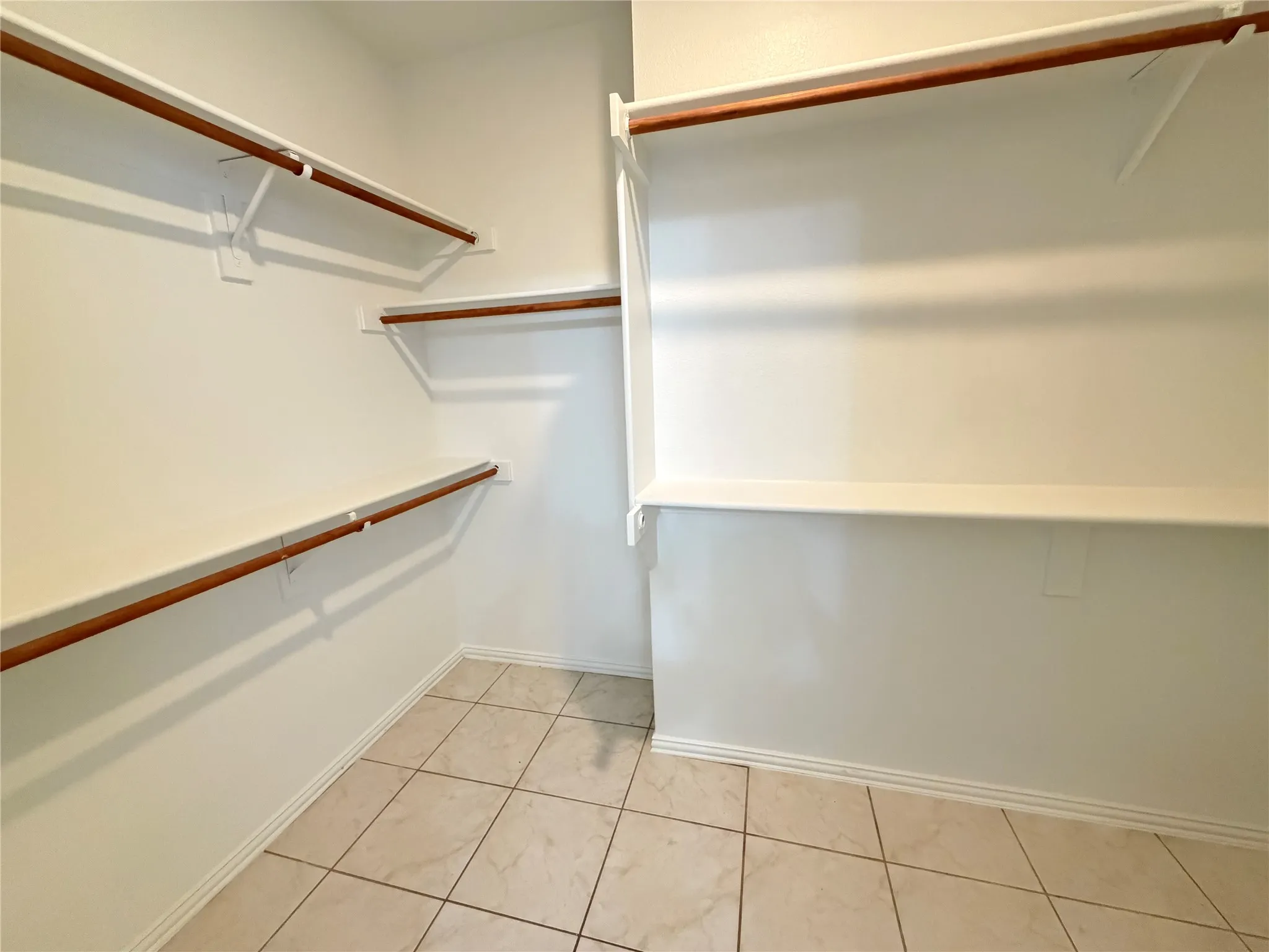 Spacious walk-in closet featuring multiple shelving units and clothing rods