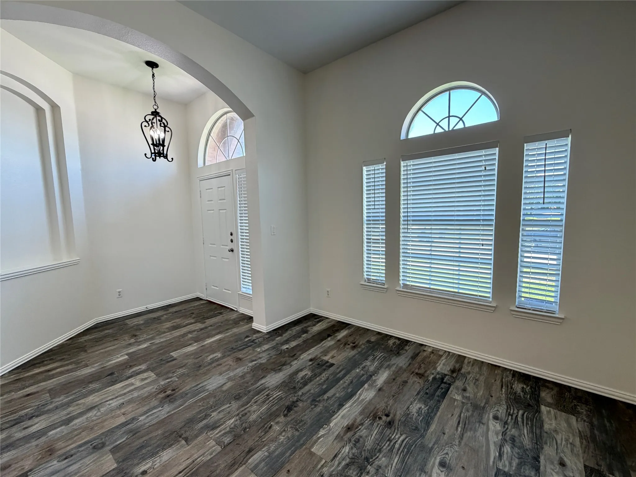 Entry area featuring wood-finish flooring, high ceilings, and arched doorways