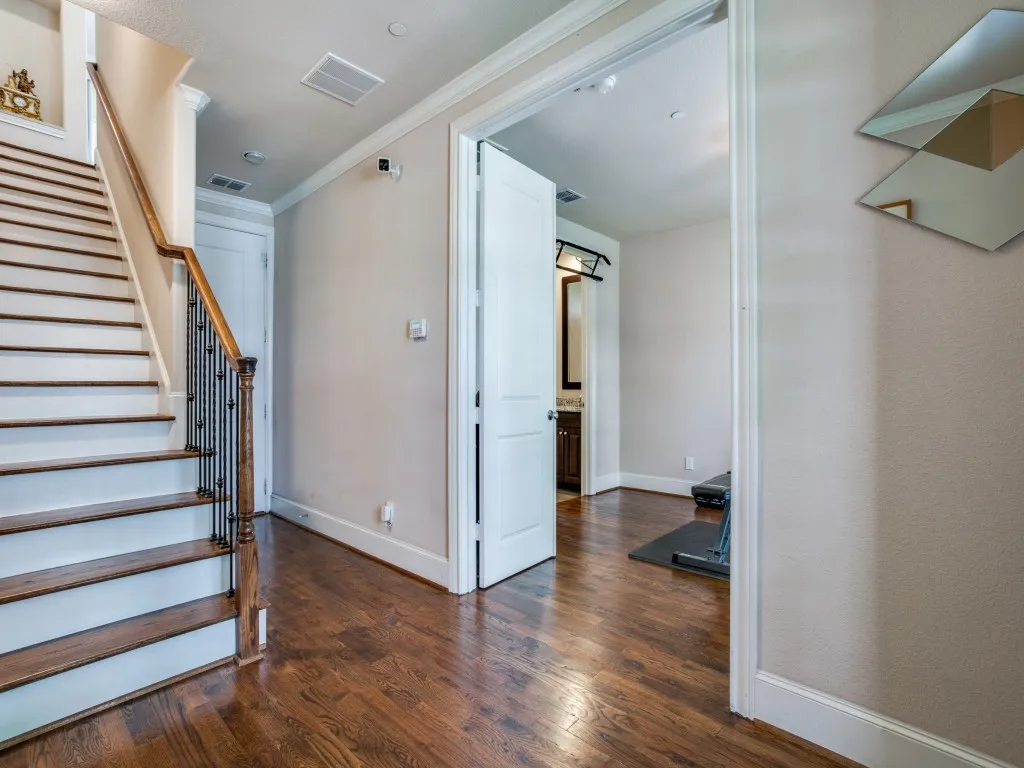 Hardwood-finish flooring, staircase with dark wood treads, white risers, and wrought iron balusters, crown molding, and white trim throughout