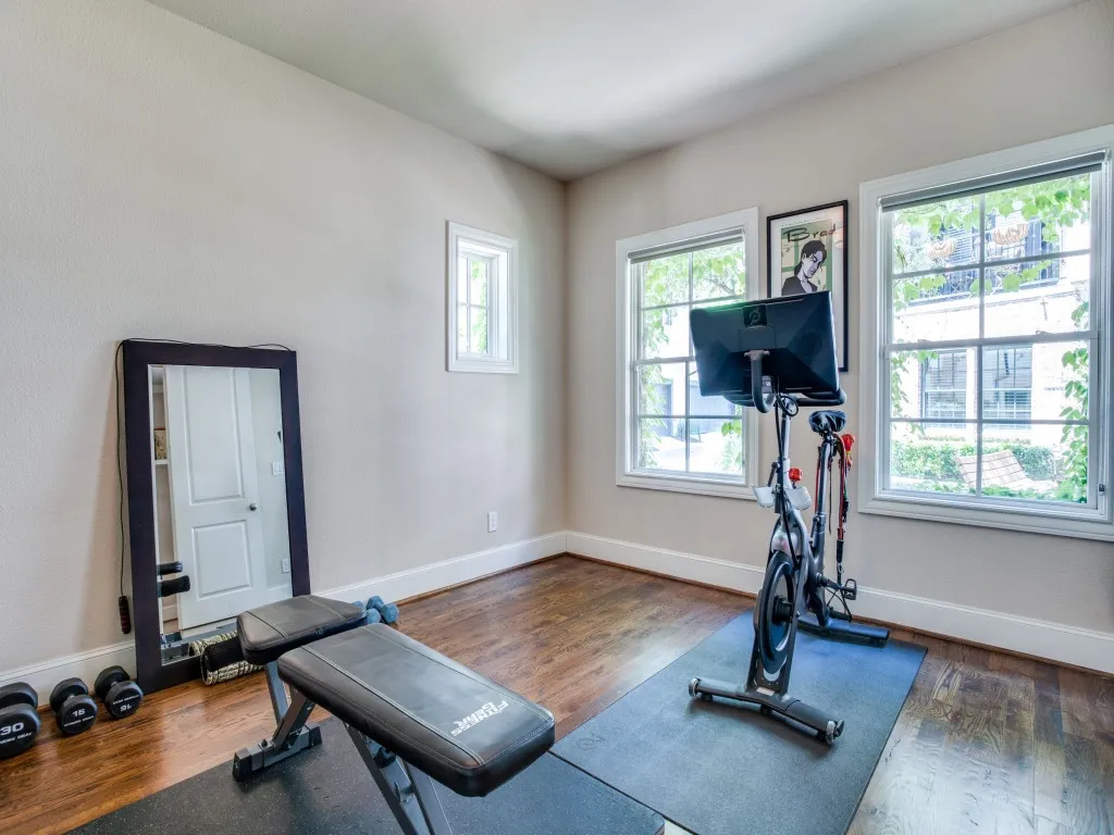 Hardwood flooring, multiple windows, window trim, baseboard molding, and neutral wall paint