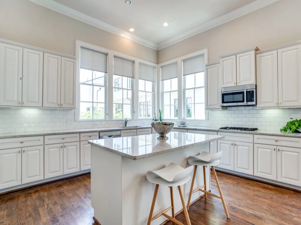 Kitchen featuring a central island, white cabinetry, a subway tile backsplash, and wood-finish flooring