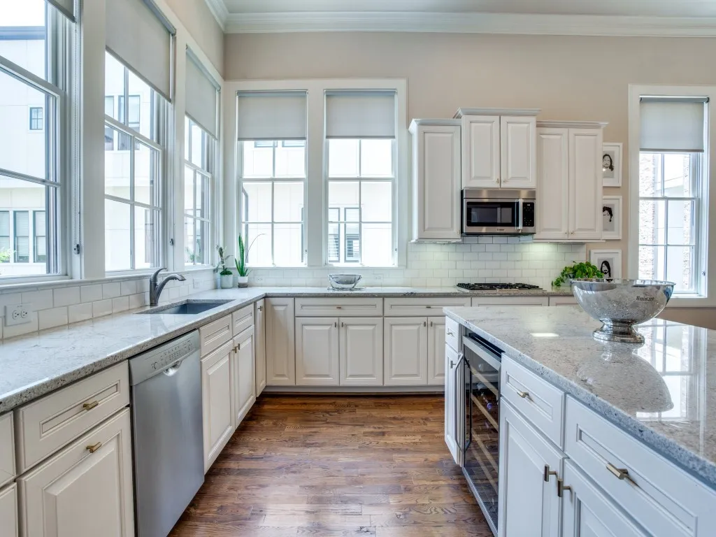 Kitchen featuring extensive counter space with light-toned stone countertops, white cabinetry, wood-finish flooring, and a built-in wine refrigerator