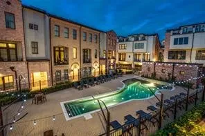 Central courtyard featuring a free-form swimming pool, extensive paving, and string lighting