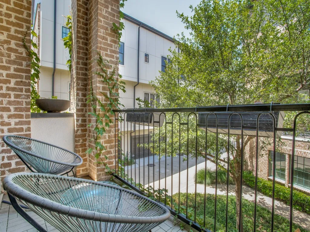 Balcony with brick columns, wrought iron railing, and a wood-finish floor