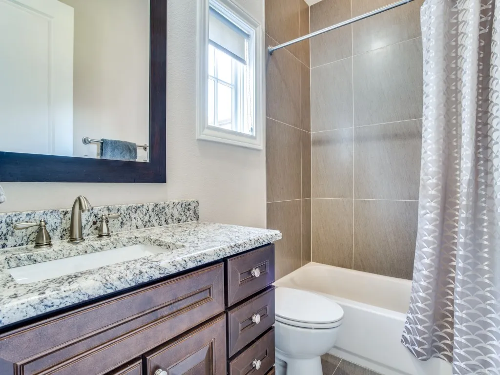 Vanity with integrated sink, speckled countertop, and dark wood-finish cabinetry