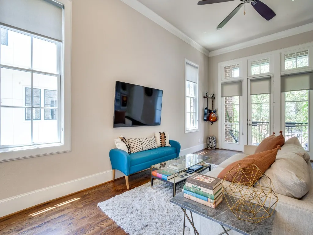 Wood-finish flooring, crown molding, double-hung windows, glass-panel French doors, and a ceiling fan with light fixture
