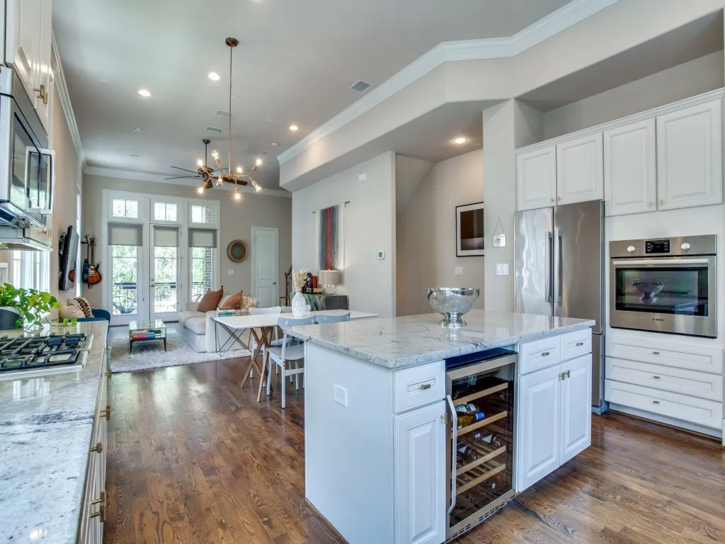 Kitchen featuring granite countertops, stainless steel appliances, white cabinetry, a built-in wine refrigerator, and wood-finish flooring