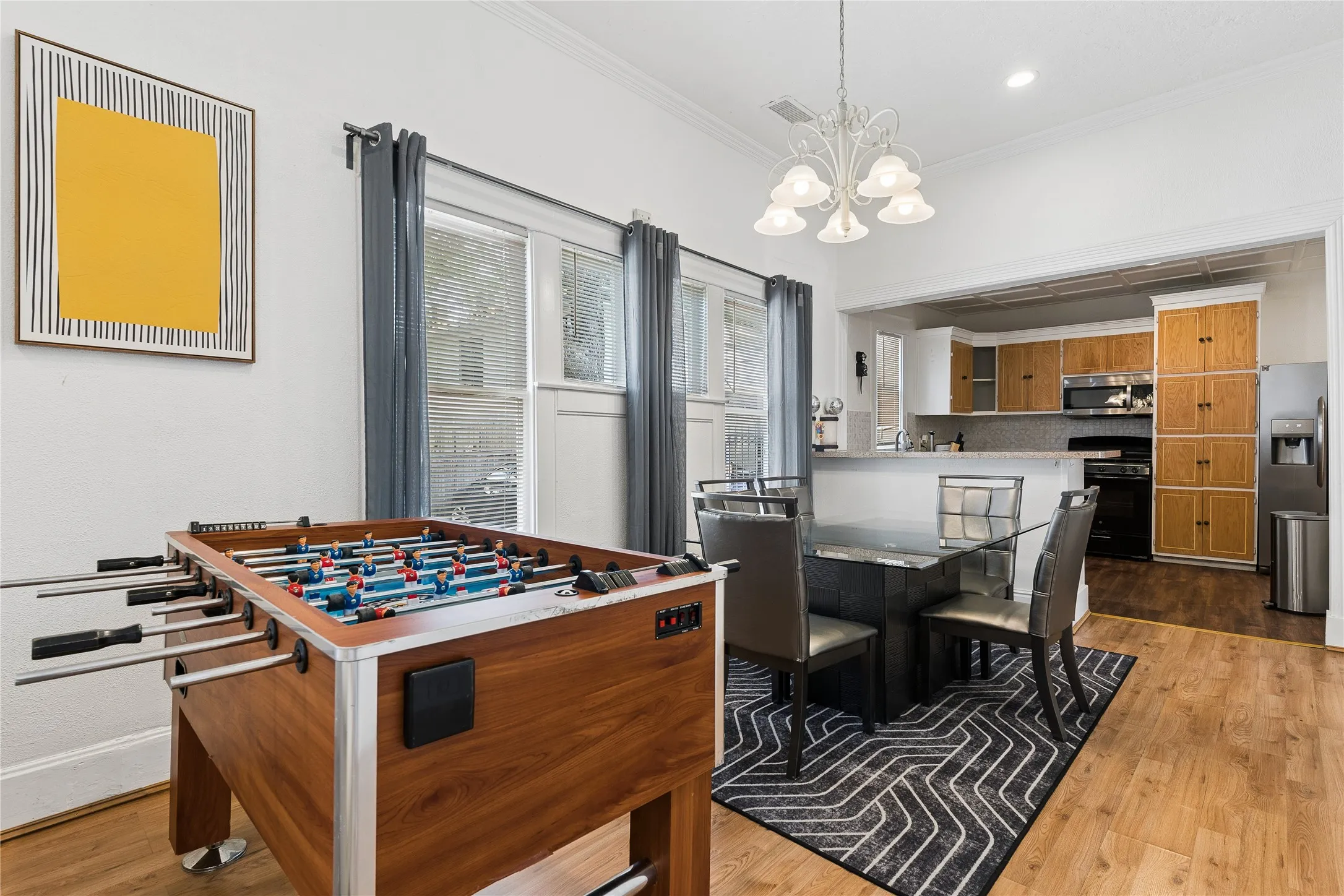 Wood-finish flooring throughout, with a dining area featuring a chandelier and direct sight to the kitchen