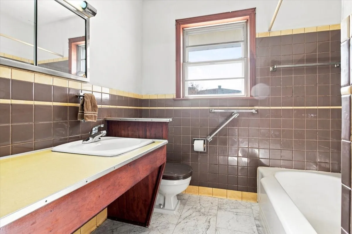 Vintage hall full bathroom featuring wood-finish vanity, tiled walls, and a built-in tub

