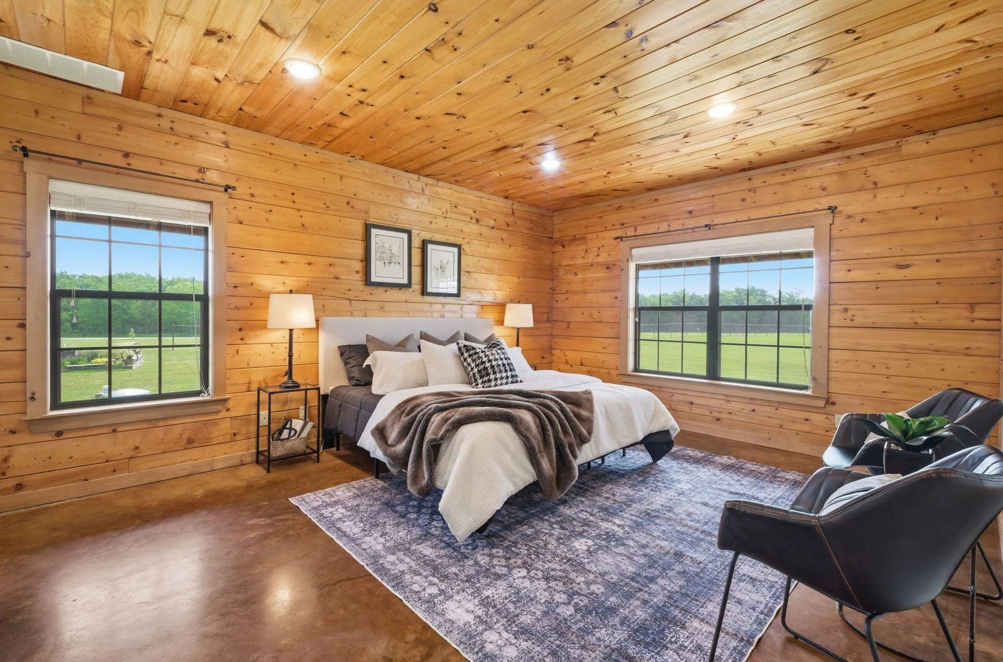 Pine wood paneling on walls and ceiling, two large windows, recessed lighting, and polished concrete flooring