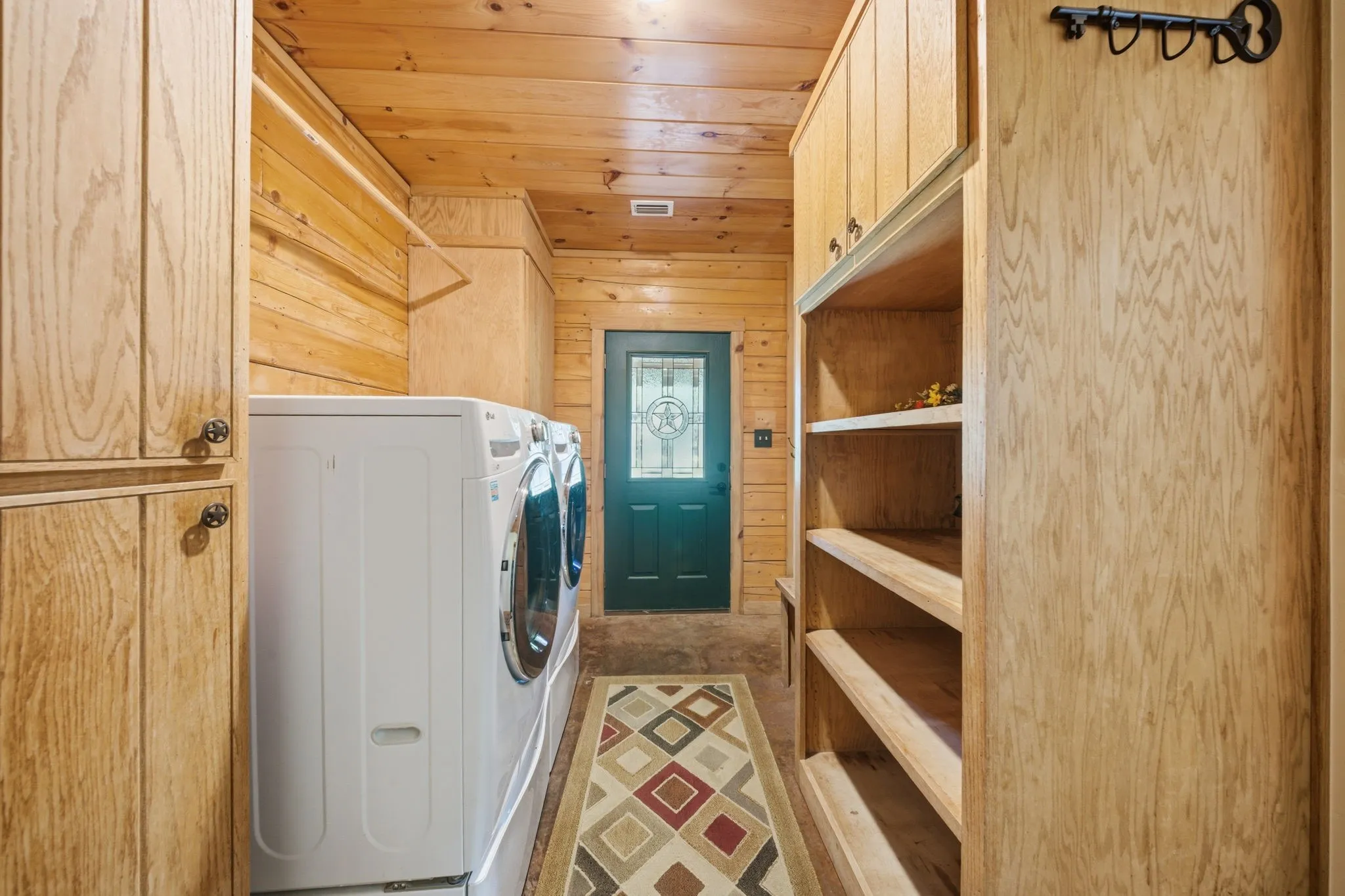 Wood-paneled room featuring built-in cabinetry, open shelving, and a dark green entry door with a decorative glass insert