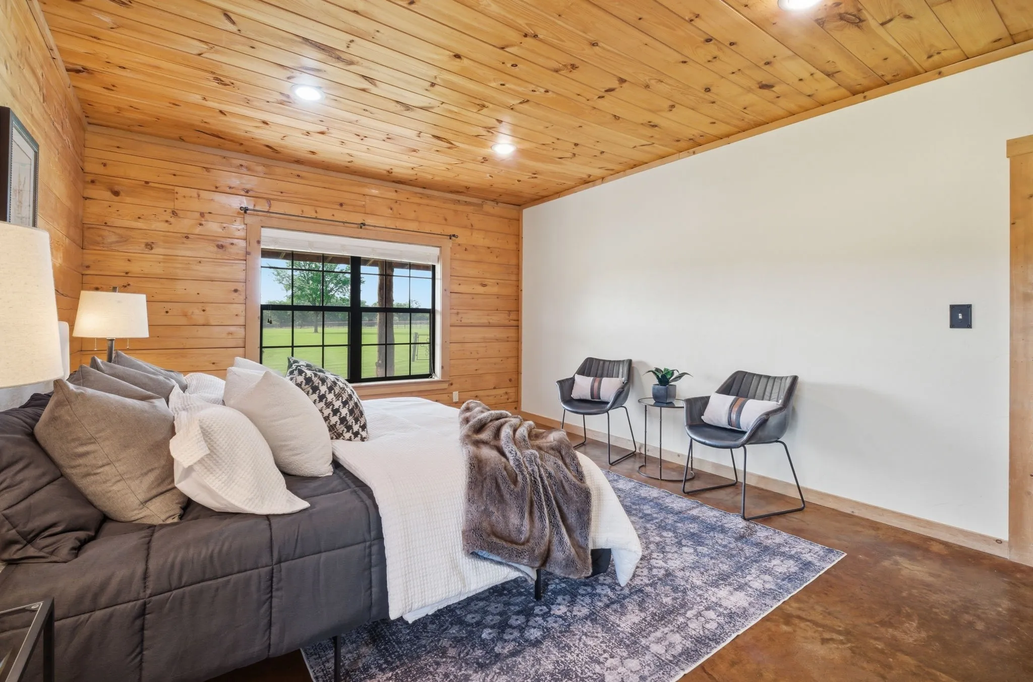 Wood-paneled accent wall, wood-paneled ceiling, recessed lighting, and a large window with black framing