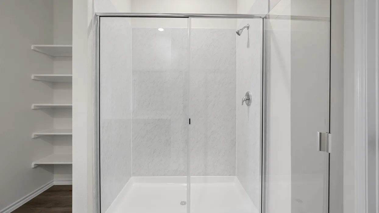 Shower enclosure with clear glass doors, white shower pan, and chrome fixtures
