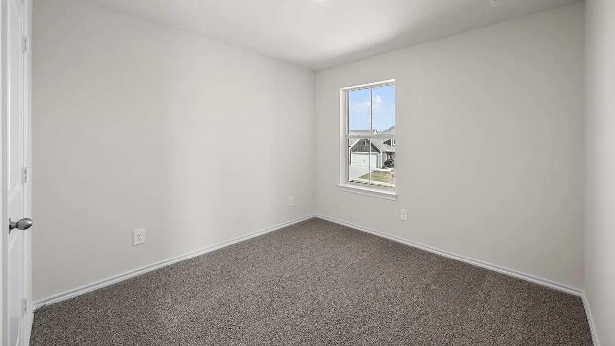 Neutral wall finishes with a single window and durable carpet flooring