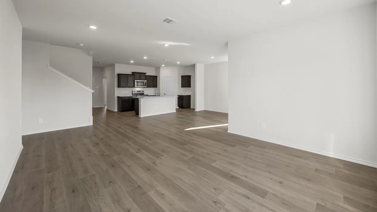 Wood-finish flooring throughout, recessed lighting, and a kitchen featuring a central island, dark cabinetry, and stainless steel appliances