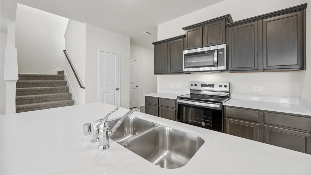 Kitchen featuring an integrated stainless steel double basin sink, chrome faucet, and white countertops