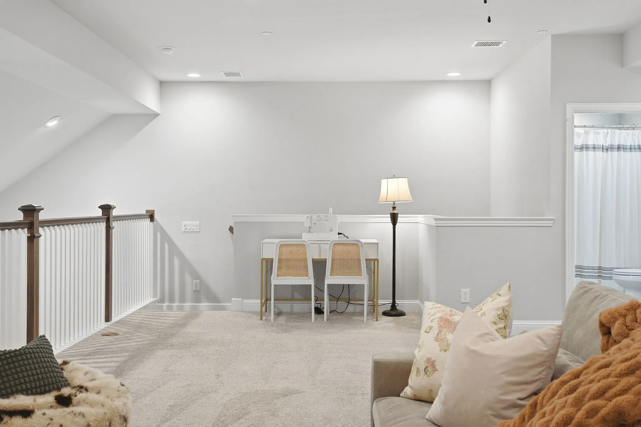 Carpeted loft area with recessed lighting, white walls, and a wood and white spindle railing