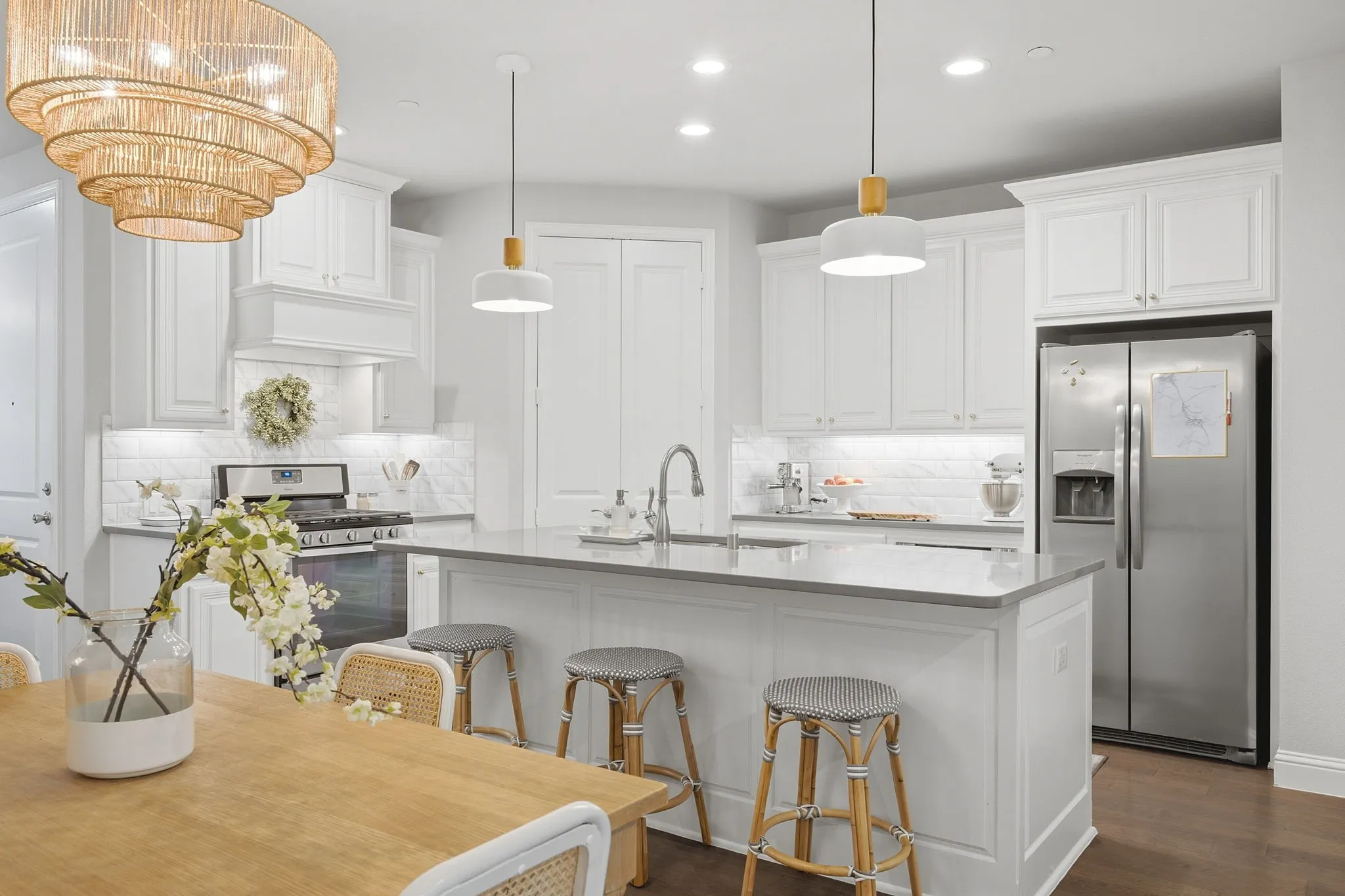White cabinetry, stainless steel appliances, central island with seating, pendant lighting, and recessed lighting