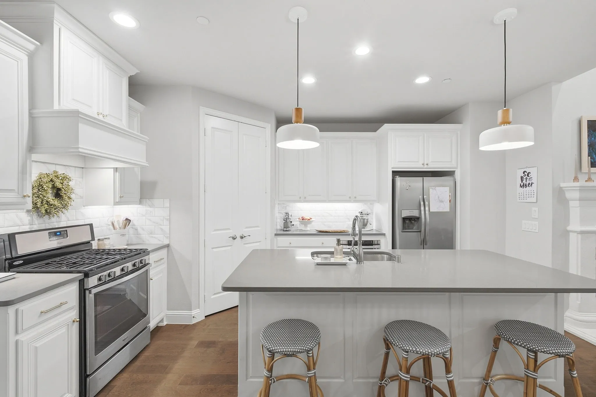 Kitchen featuring white cabinetry, stainless steel appliances, a large center island with a sink, and pendant lighting