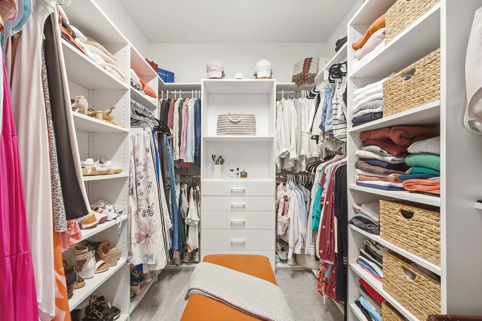 Built-in shelving, multiple hanging rods, integrated drawers, and wood-finish flooring