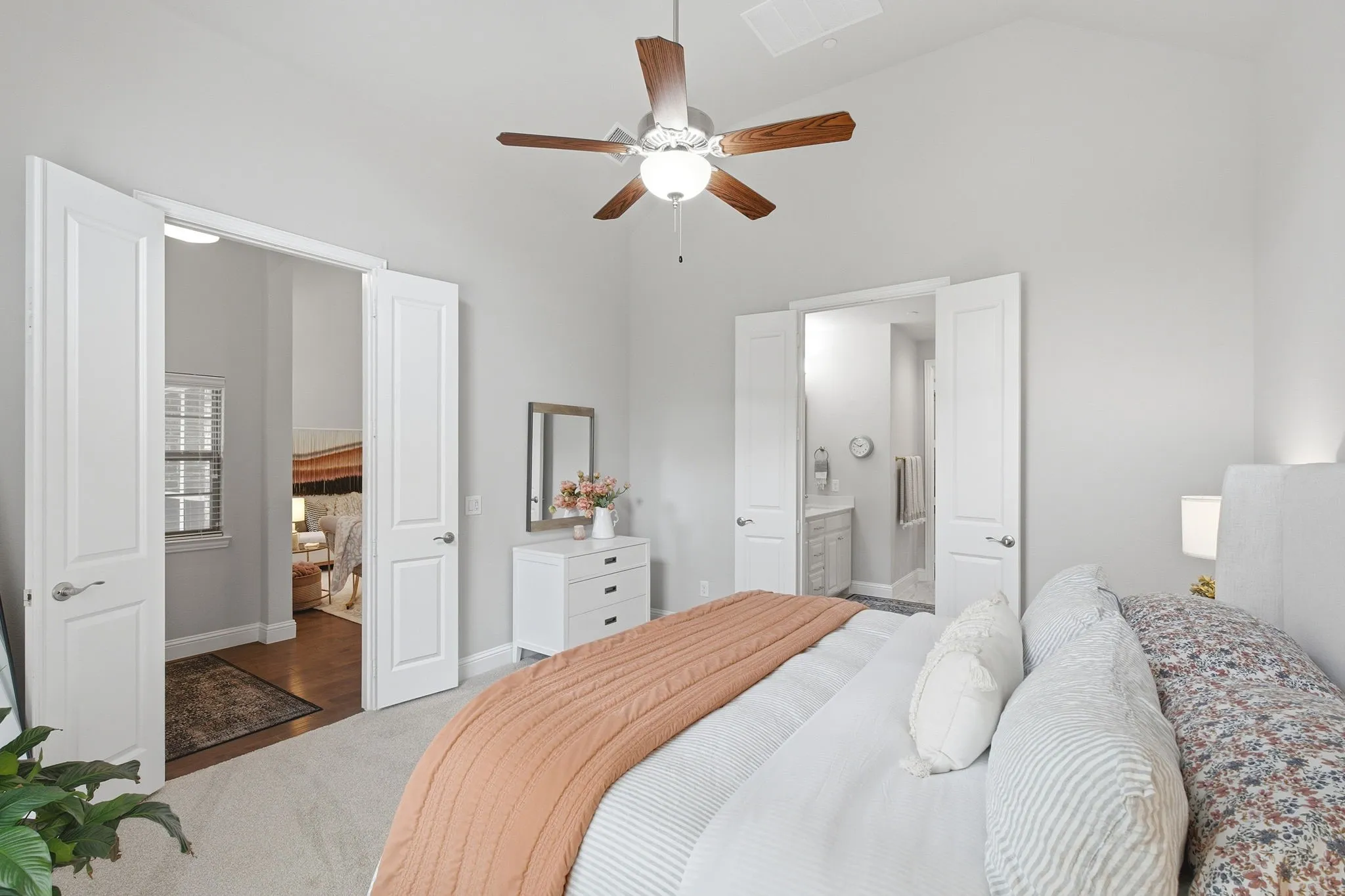 Vaulted ceiling, ceiling fan with light fixture, carpeted flooring, double-door entry, and a built-in window with horizontal blinds